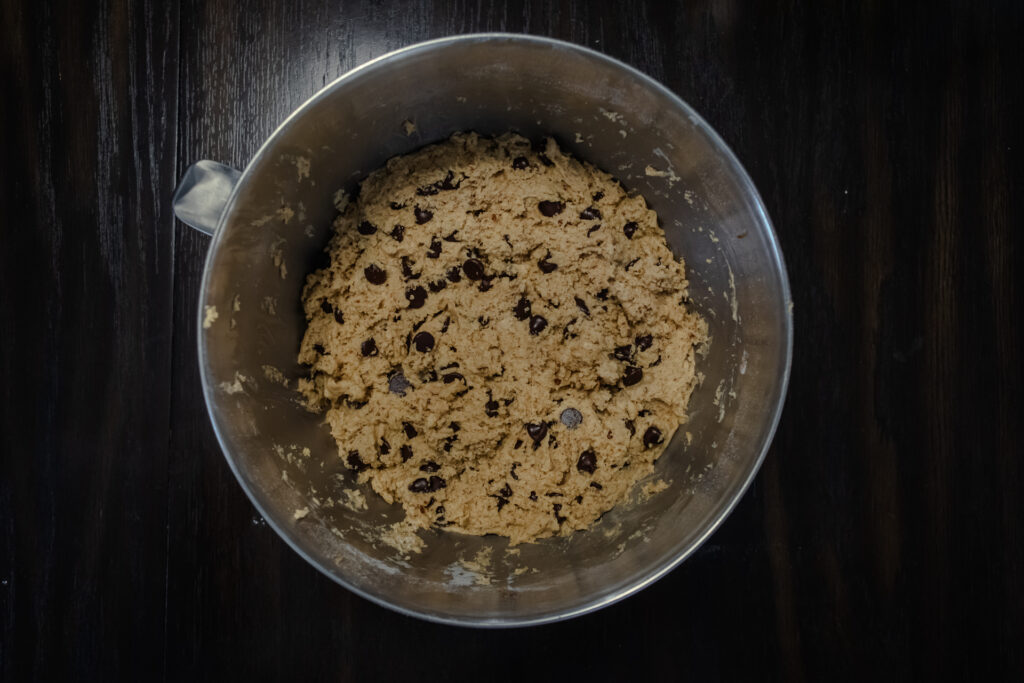 An overhead shot of chocolate chip cookie dough in a large steel bowl