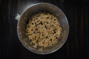 An overhead shot of chocolate chip cookie dough in a large steel bowl