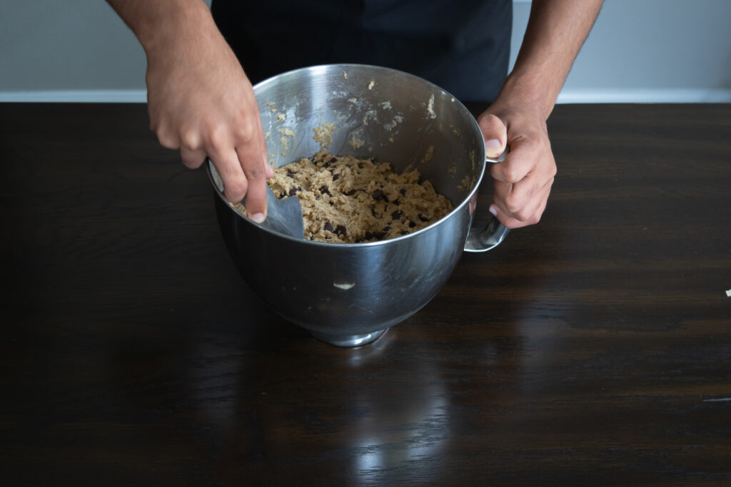 A person scooping chocolate chip cookie dough