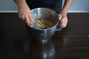 A person scooping chocolate chip cookie dough