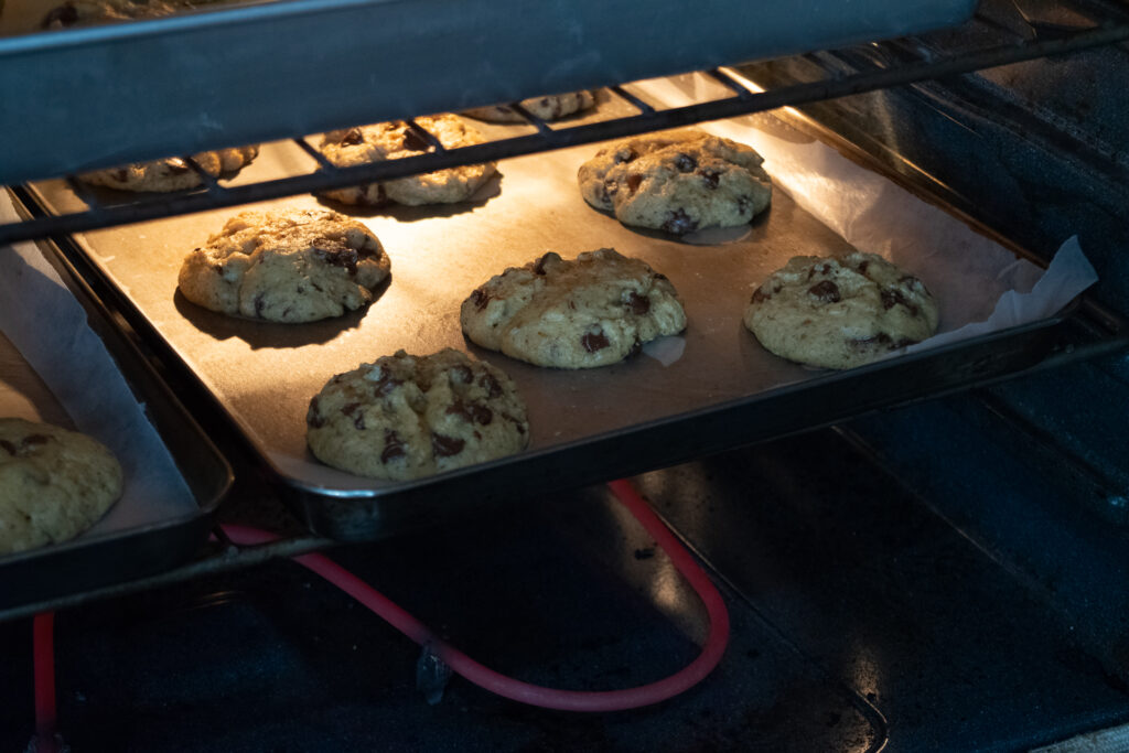 Chocolate chip cookies baking in an oven.